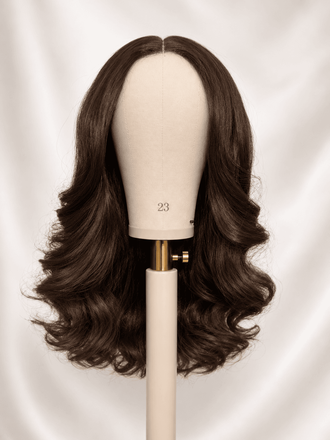 Curly brown wig after revival on a mannequin head, defined and glossy