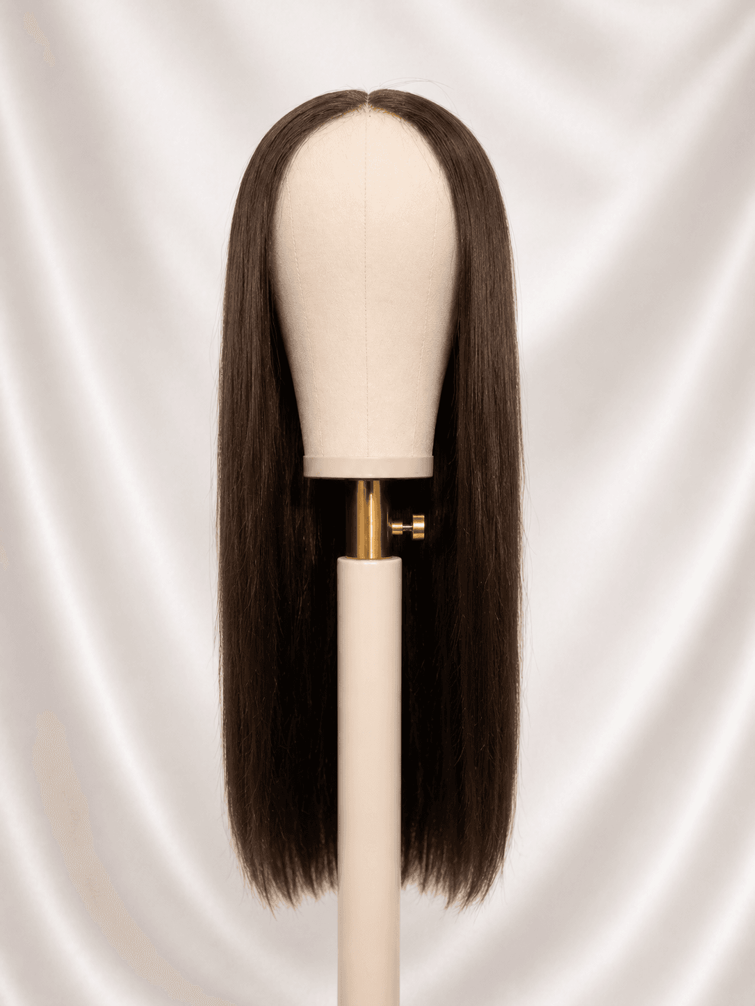 Long straight brown wig after restoration on a mannequin head, sleek and smooth